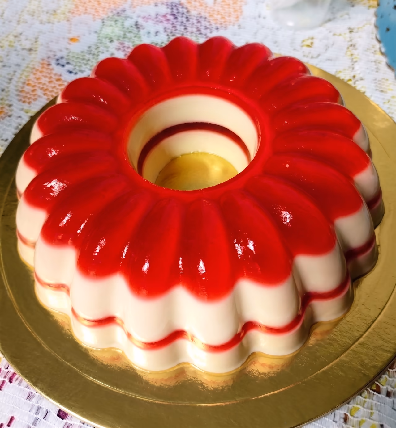 Gelatina en molde de flor, roja arriba y crema abajo, sobre base dorada